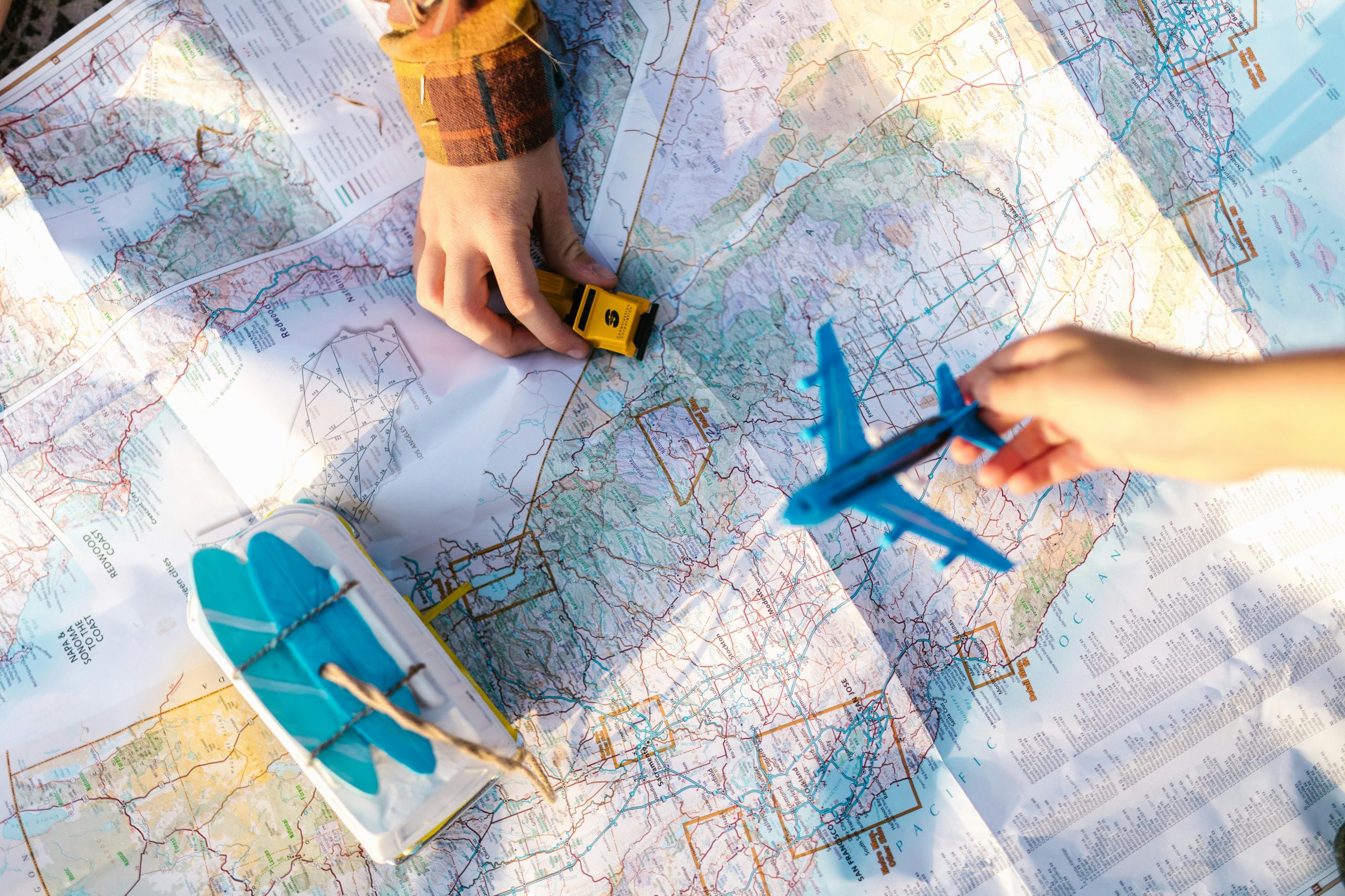 Children playing with a toy airplane and car on a map, illustrating a student project designed with the GRASPS model for authentic tasks on human migration.
