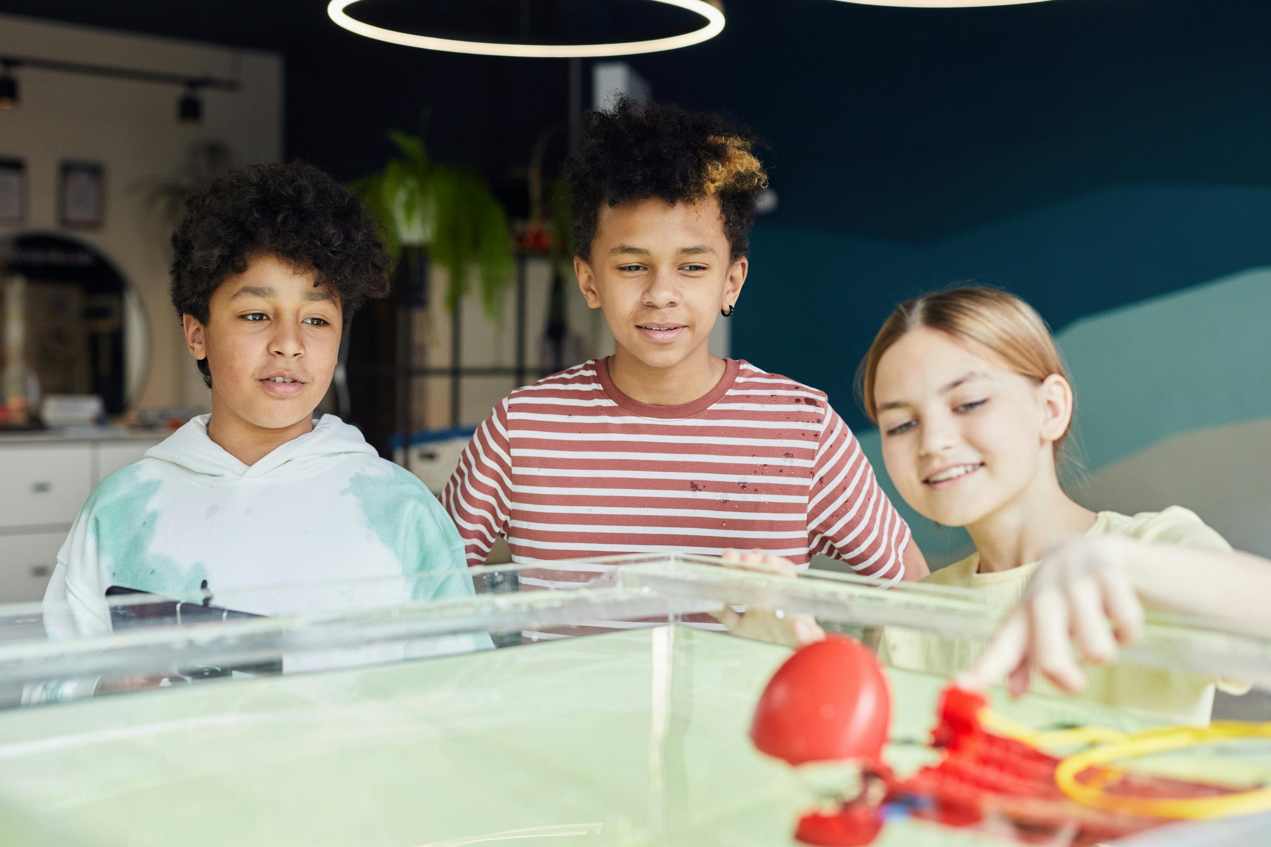 Three students investigating a hands-on science experiment, exploring cause-and-effect through real-world application.