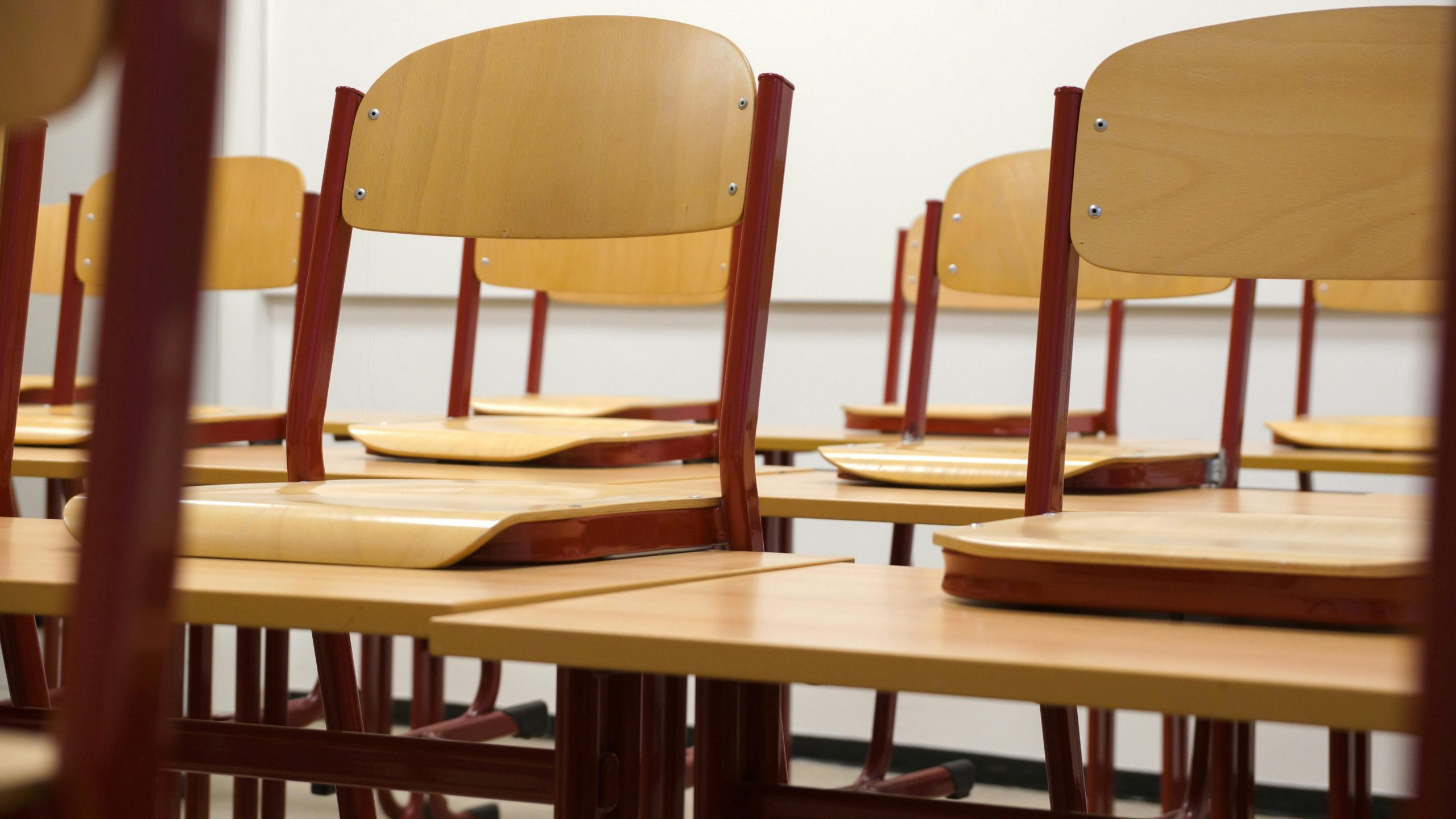 Chairs stacked upside down on top of classroom tables, ready for students to help set up the room in the morning.