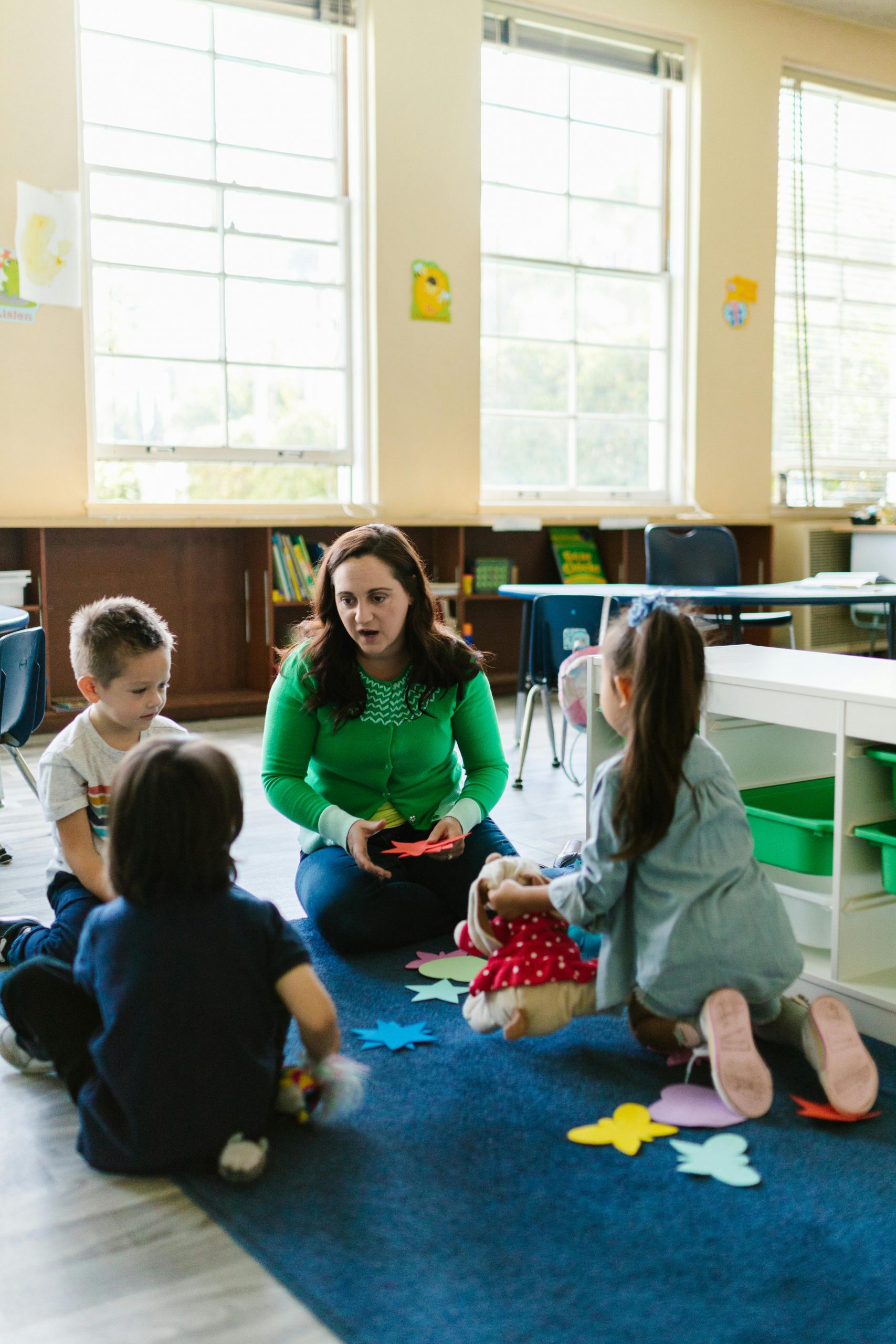 Teacher supporting students in the classroom during a small group social skills activity with paper cutouts.
